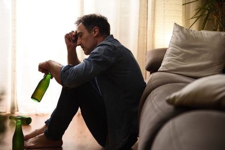 man sitting on the floor drinking after relapsing